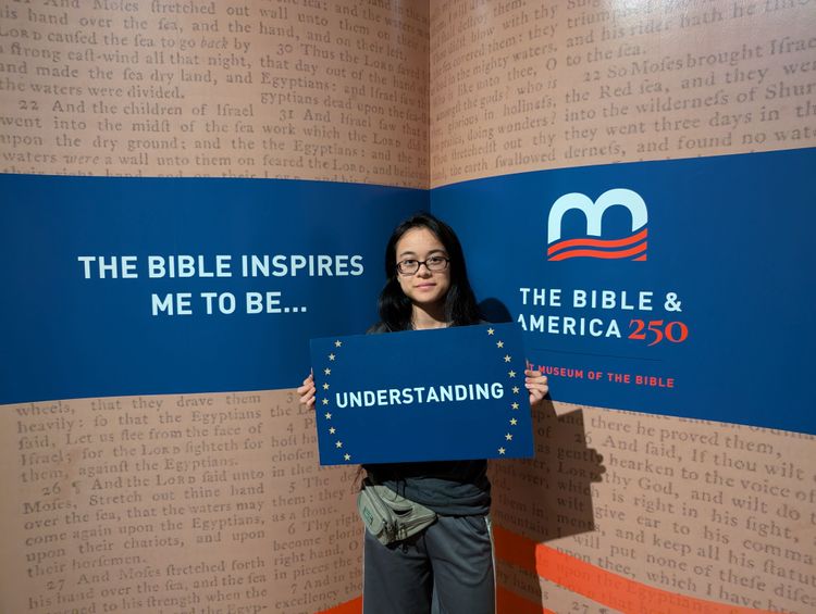 Catherine holding a sign saying "Understanding". Background words read "The Bible inspires me to be..."